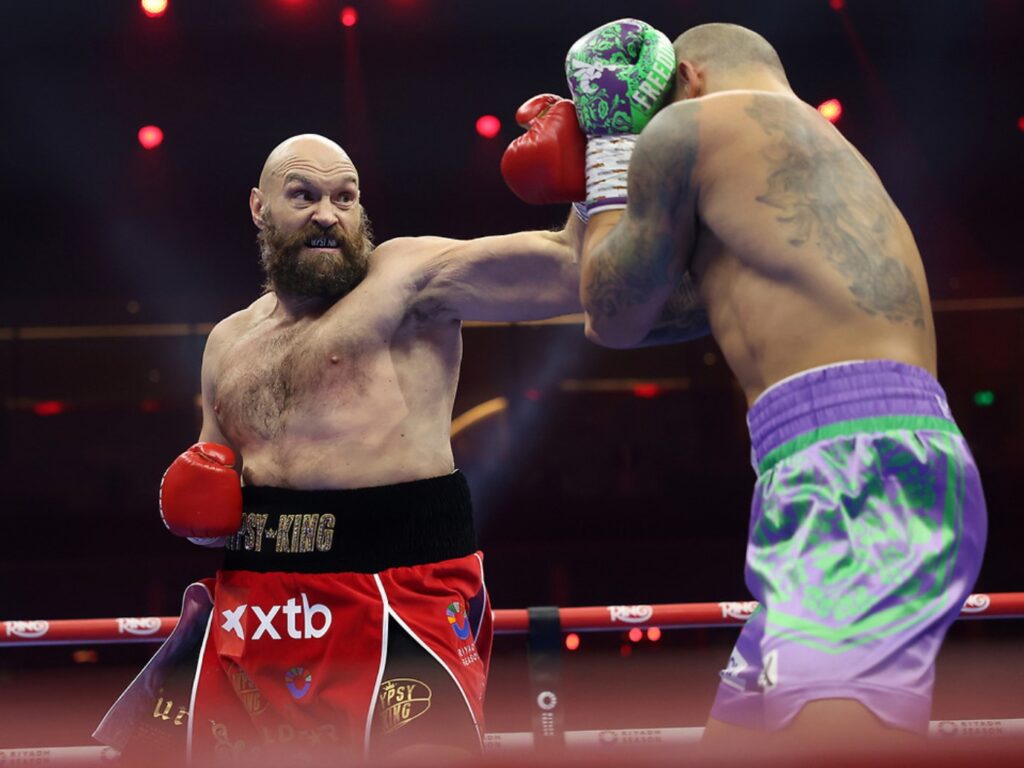 Tyson Fury en plein combat de boxe poids lourds, utilisant son jeu de jambes et sa défense atypique sur le ring