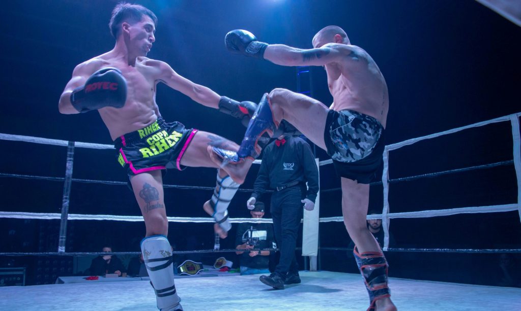 Deux combattants de boxe pieds-poings en plein échange sur un ring lors d'une compétition