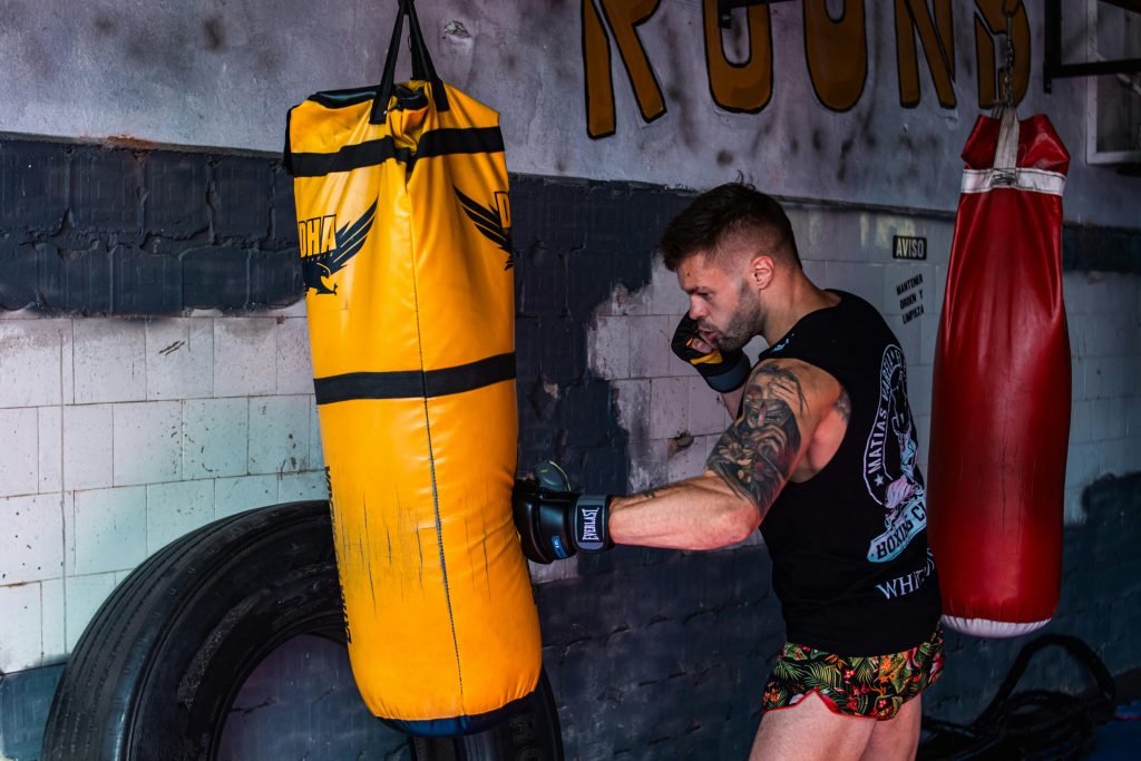 Boxeur frappant un sac de frappe jaune dans une salle d'entraînement de boxe
