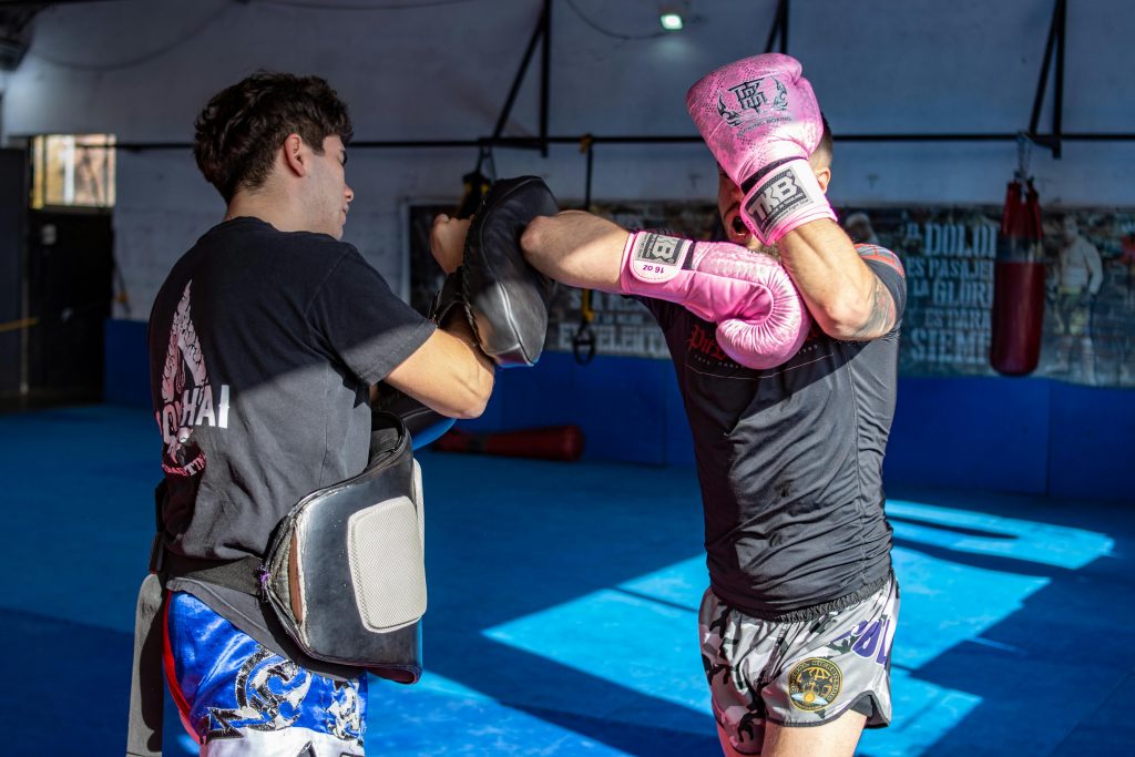 Muay-thai : coach et son nak muay s'entraînant ensemble dans une salle de boxe en coaching privé